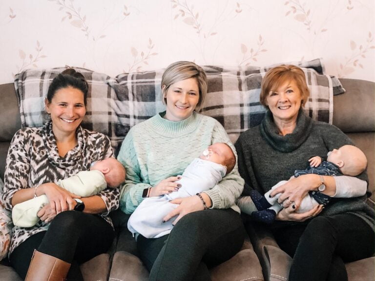 Photo of the 3 Northern Ireland Doulas sitting together on a sofa, each holding a triplet baby